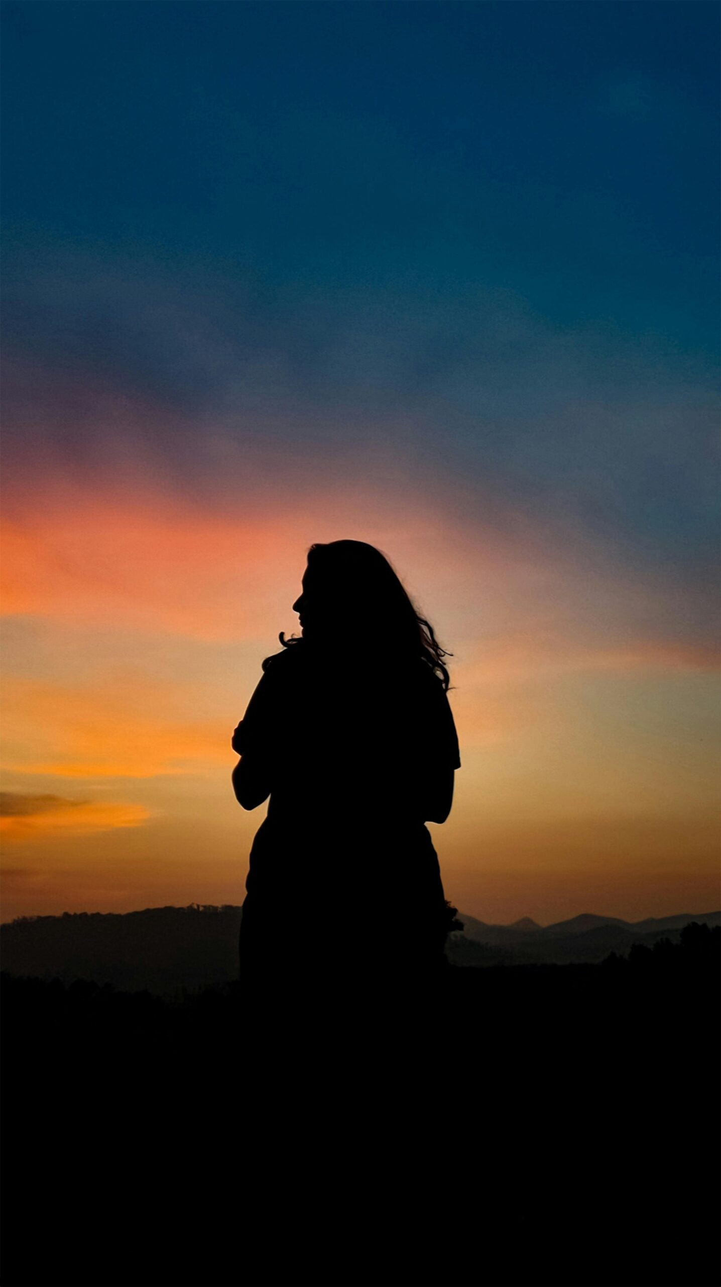 Silhouette of a woman during a vivid sunset with colorful sky.
