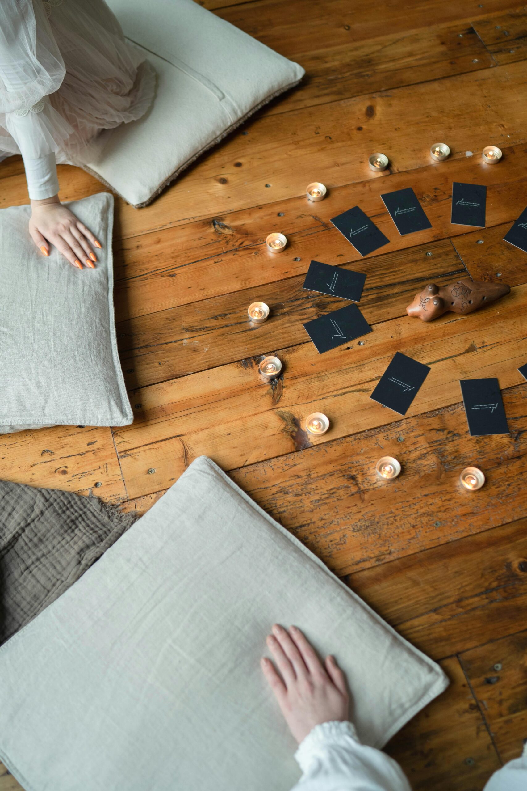 Warm indoor setting with ritual arrangement; cards and candles create cozy ambiance.